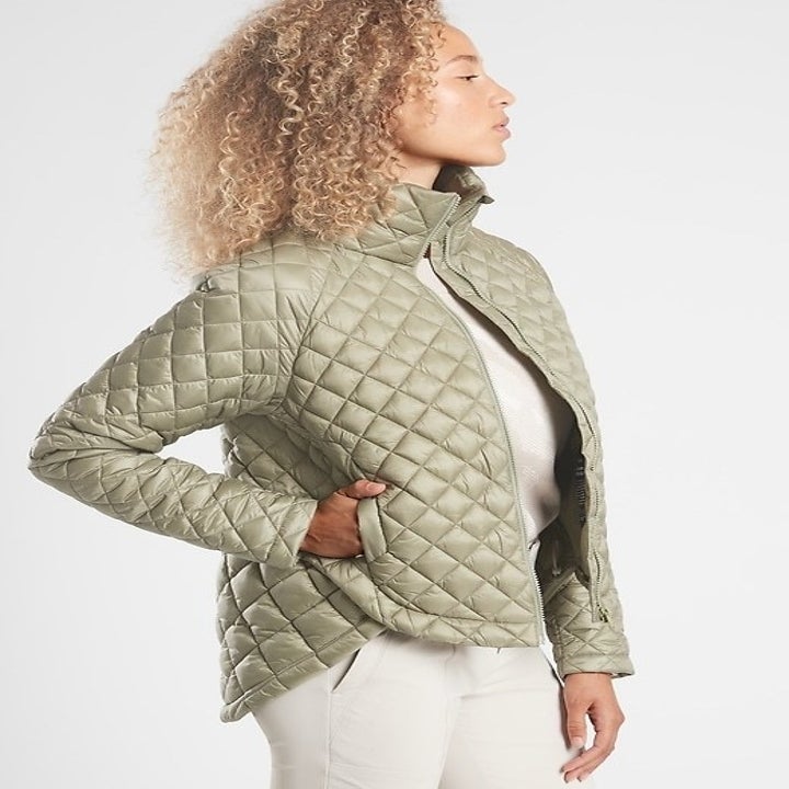 Model wearing light green quilted jacket with longer hem in the back