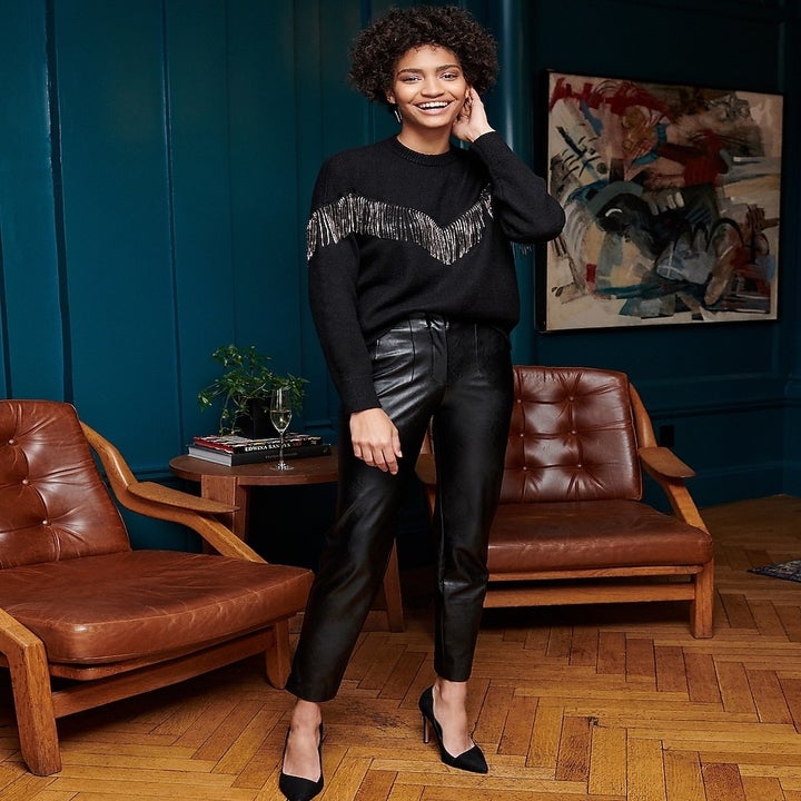 Model wearing black crewneck sweater with rhinestone fringe