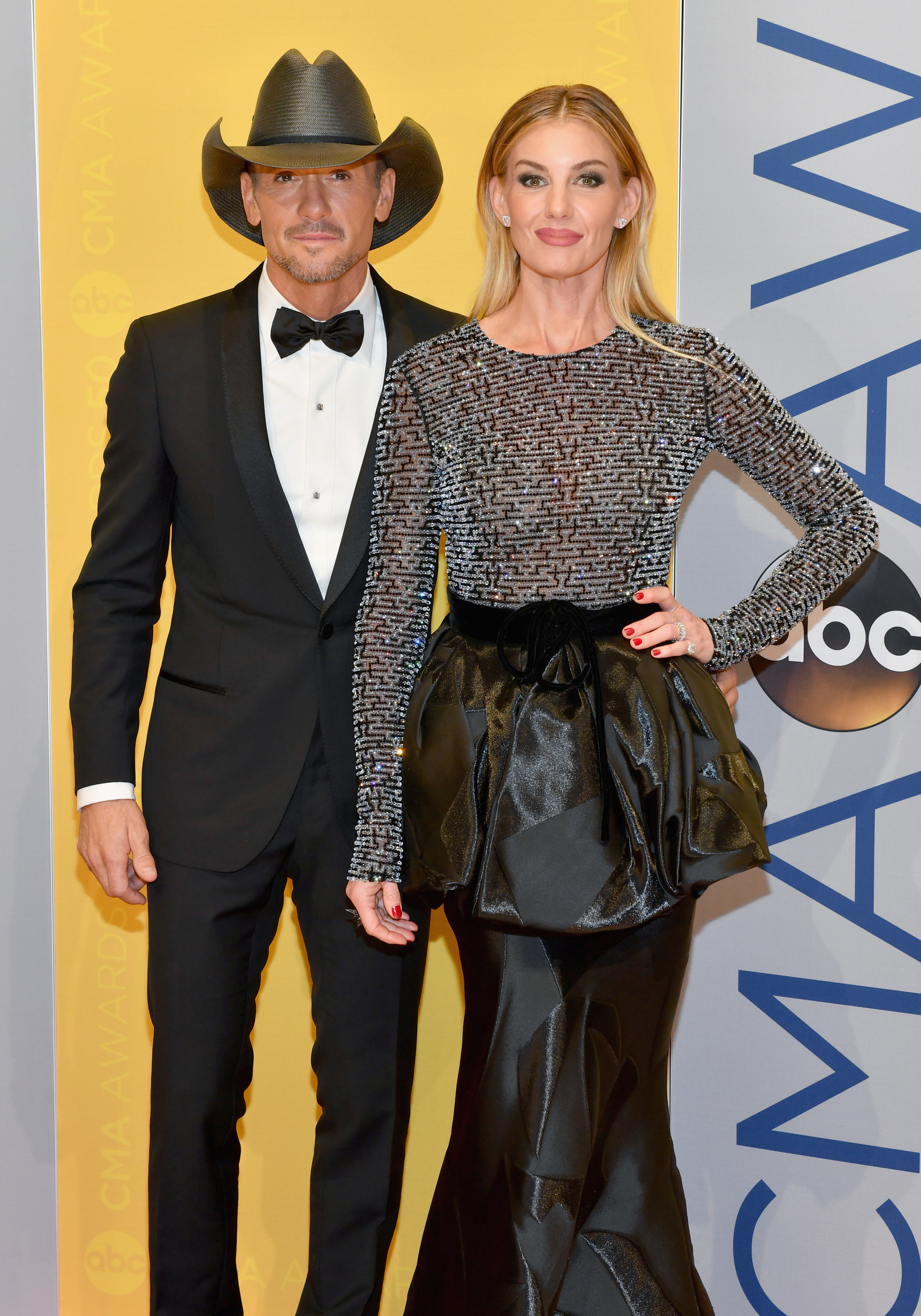 Tim, in a dark suit, and Faith, in a dress with a puffy mid section at a red carpet event