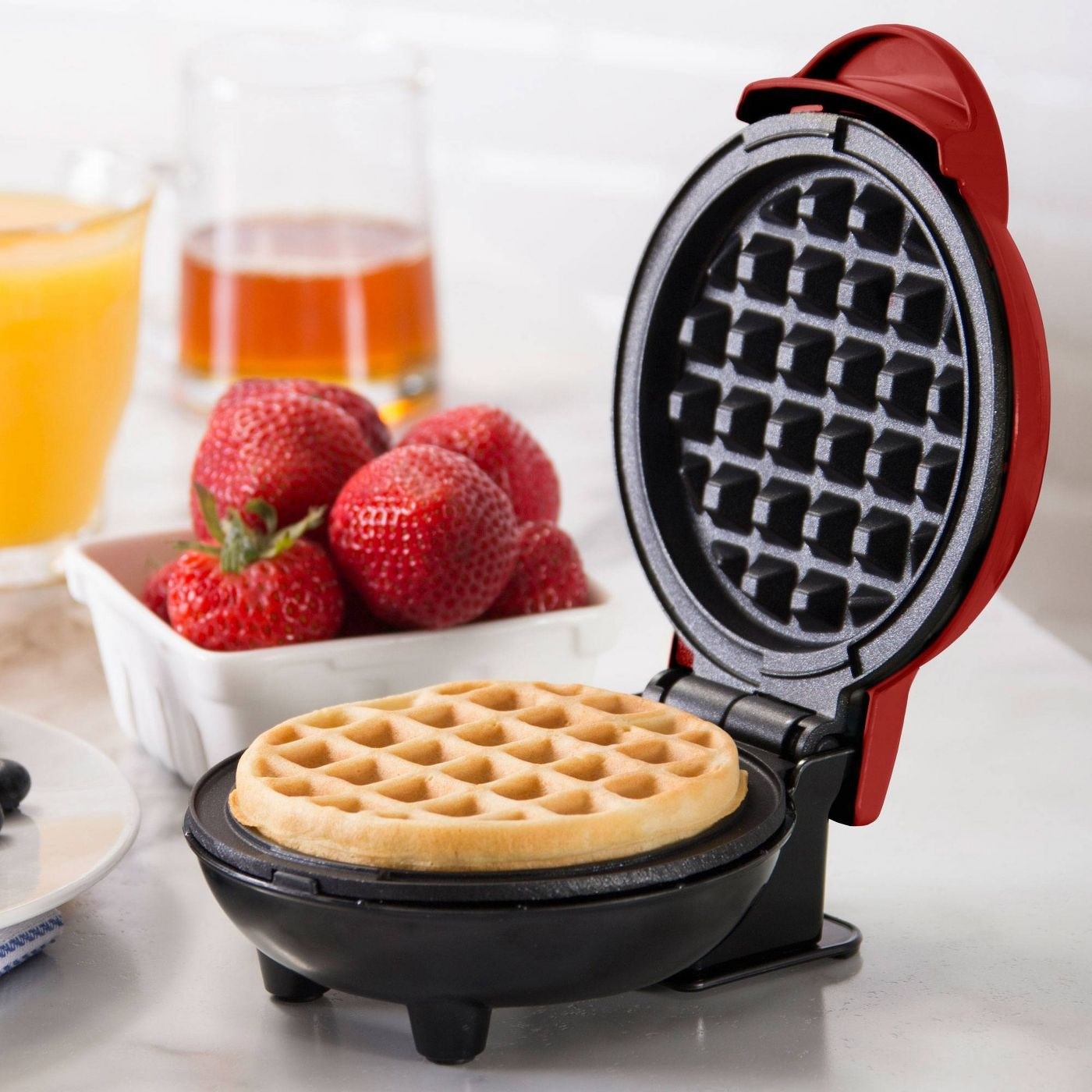 red waffle maker with a cooked waffle inside of it