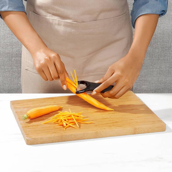 person using black y peeler to peel carrots