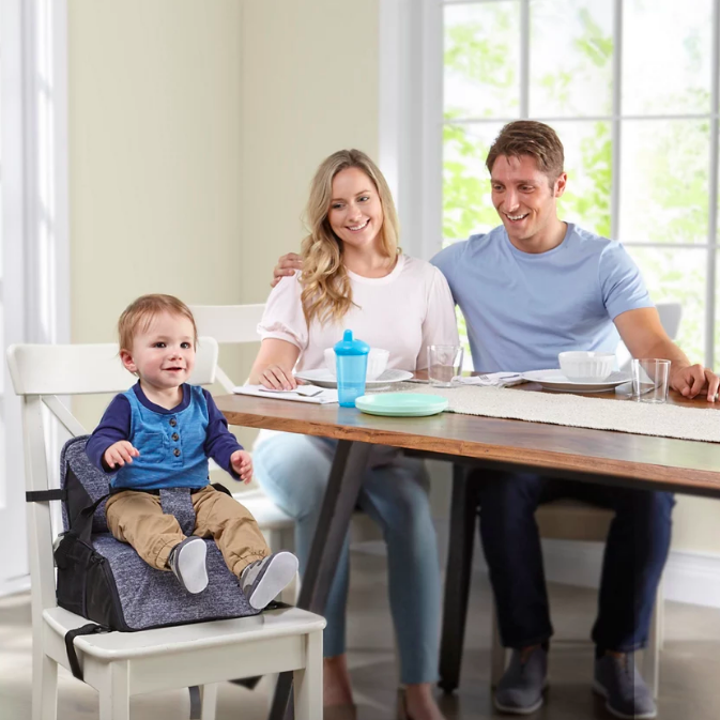 Child sitting on secured booster seat at table with family 