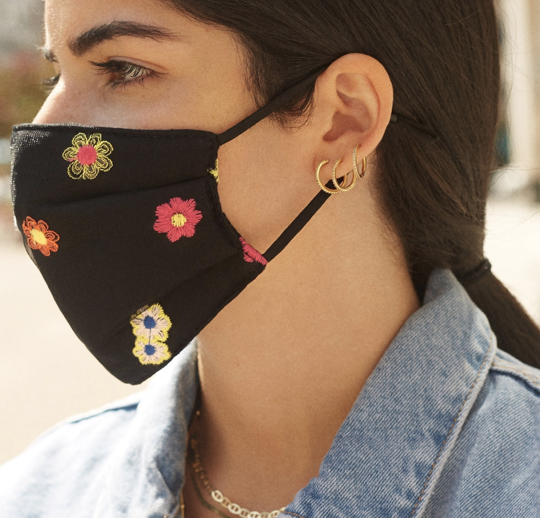 A model in a black face mask with embroidered flowers 