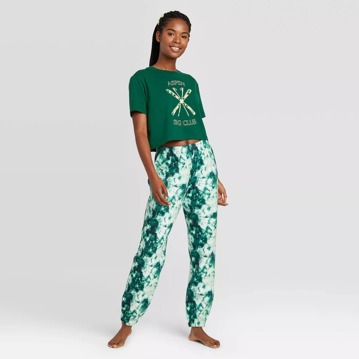 A model wearing the fleece joggers, the shirt, and the scrunchie in green