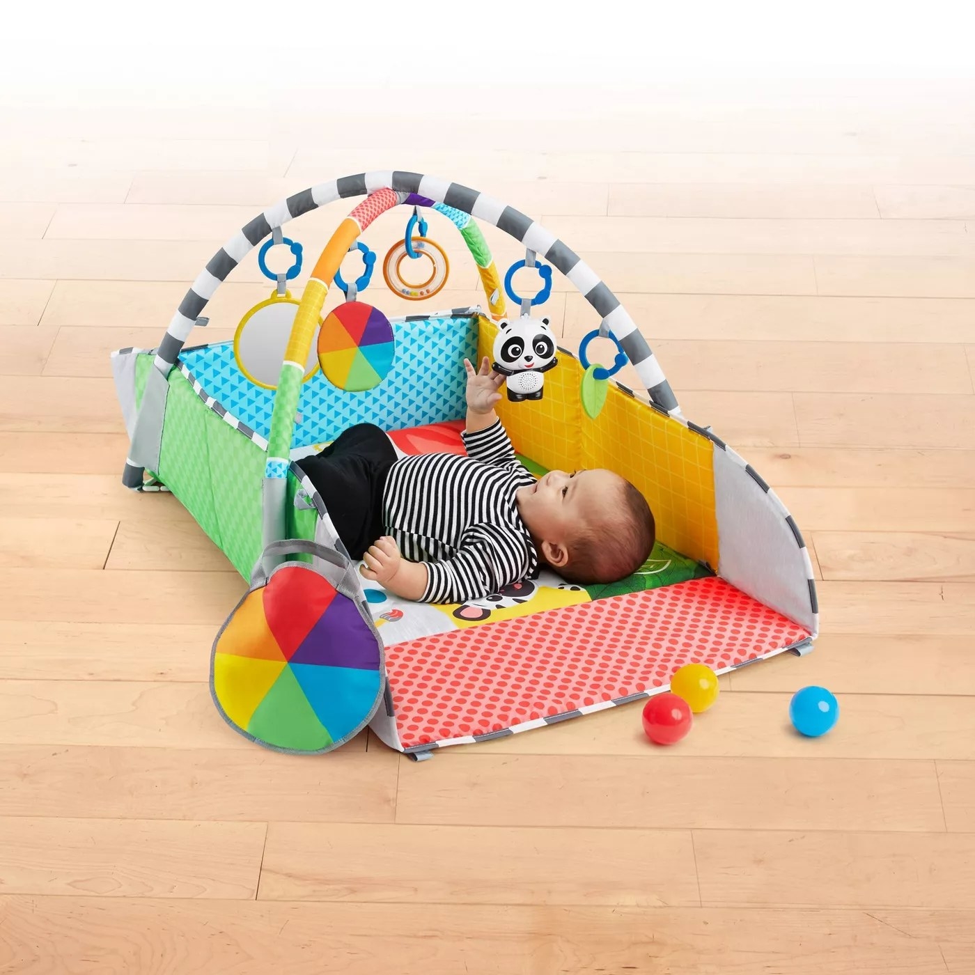 A baby playing with the hanging toys on the play gym