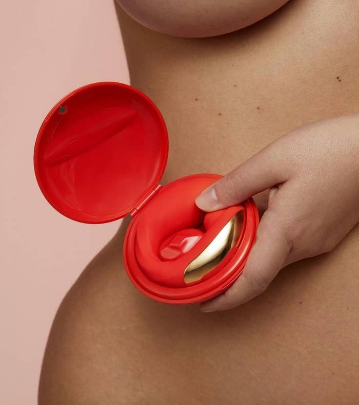 A model holding the red and gold vibrator in its matching red clamshell case