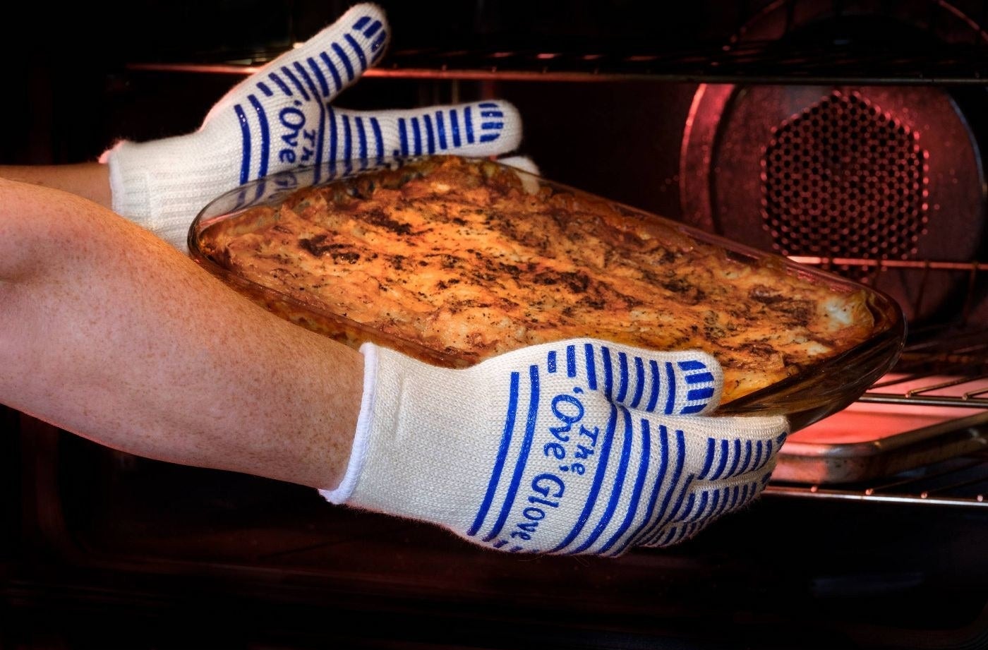 person using ove gloves to handle a hot pan coming out of an oven