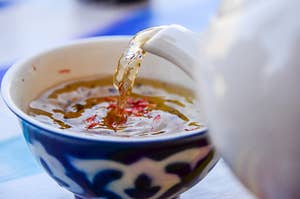 Someone pouring tea into a cup with a blue and white floral design