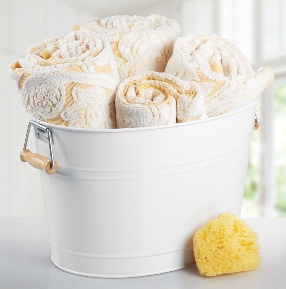 White tub with tan wooden handles displays white and yellow towels