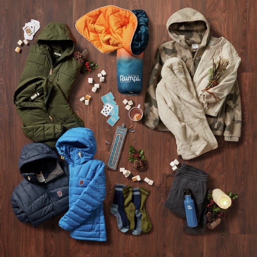 flatlay of an outdoor blanket, hiking socks, outdoor clothing, a water bottle, and a cribbage set