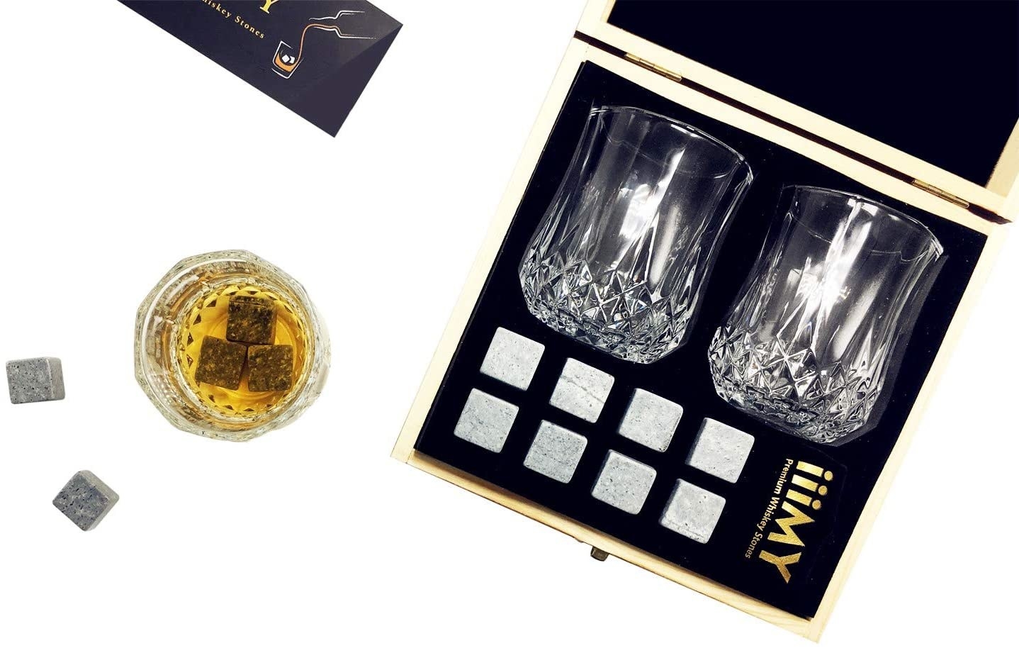 A flatlay of the open gift box containing two crystal etched glasses and eight whiskey stones
