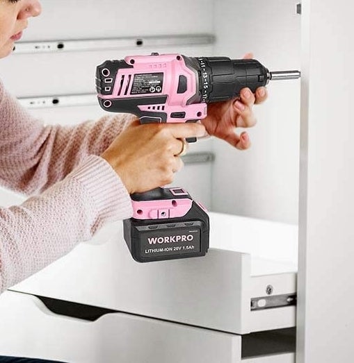 A person drilling into a set of drawers