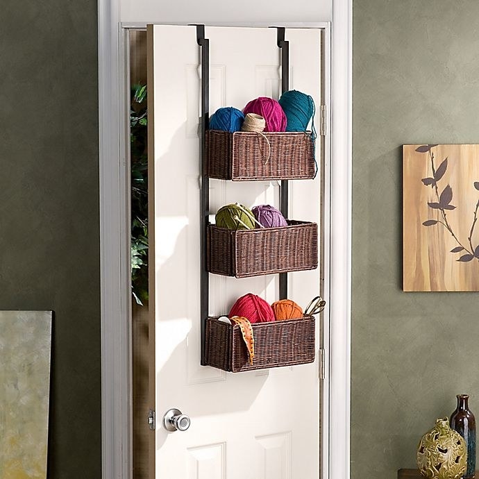 the Southern Enterprises Over-The-Door 3-Tier Basket Storage handing on the back of a door