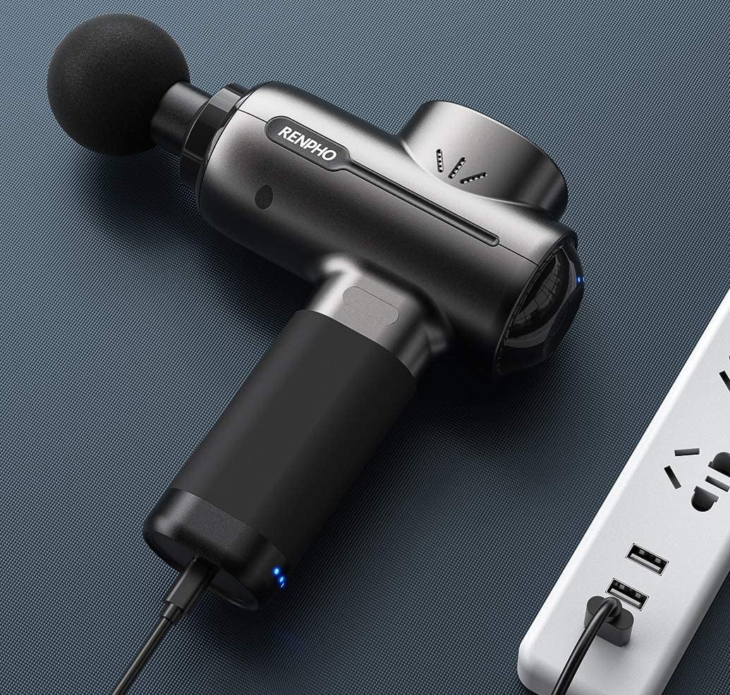 A massage gun plugged into an outlet