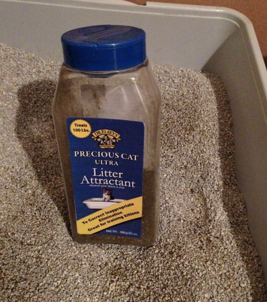 The bottle of litter attractant sitting in a litter box