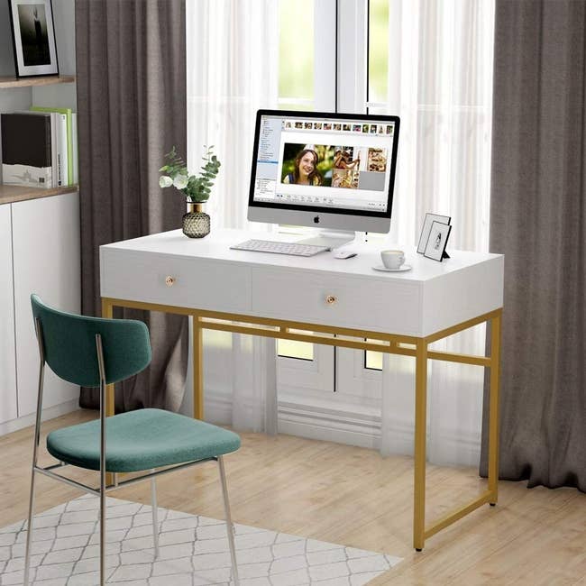 white desk with two front drawers and gold legs