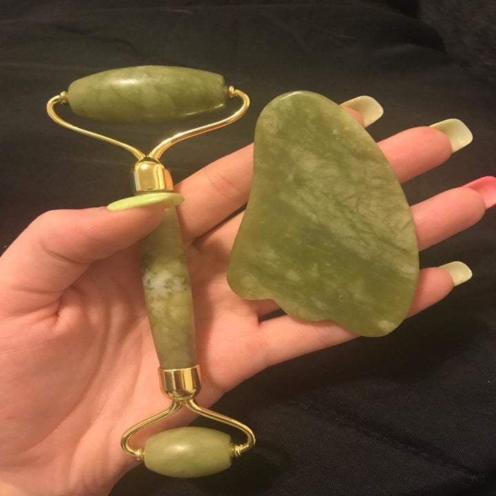 Reviewer holds same jade roller and a green gua sha in their hand