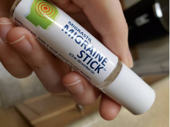 Reviewer holding lip balm-sized tube of roll on migraine stick 