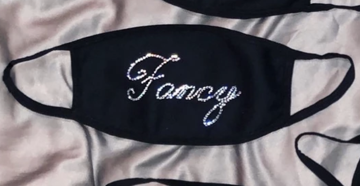 A black face mask with bedazzled message that says &quot;fancy&quot; 