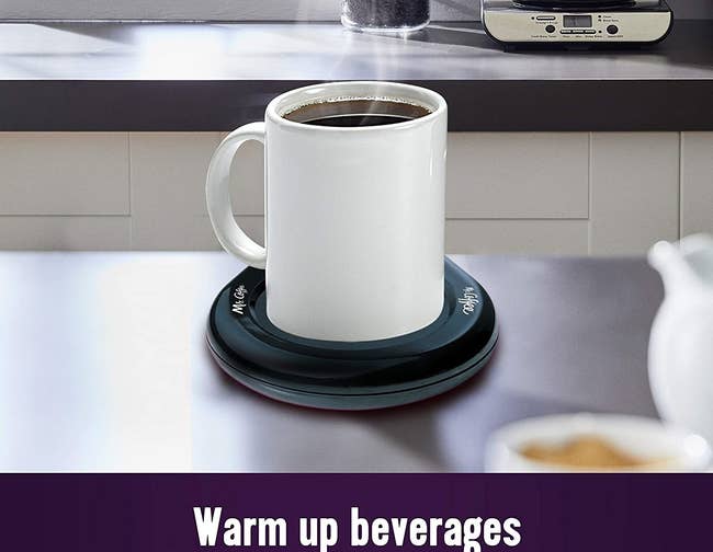 A mug on a black round mug warming surface on a table 