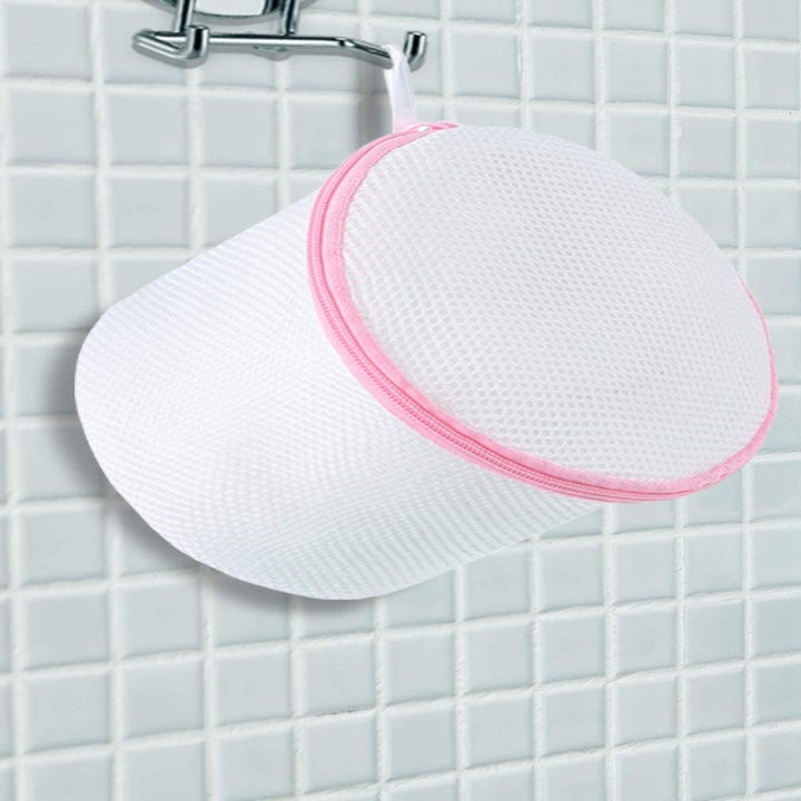 One of the mesh bags with pink trim hanging from a hook in a shower 