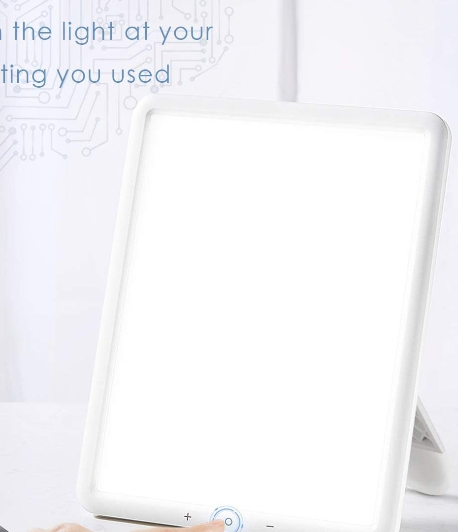 person pressing the power button on the light therapy lamp