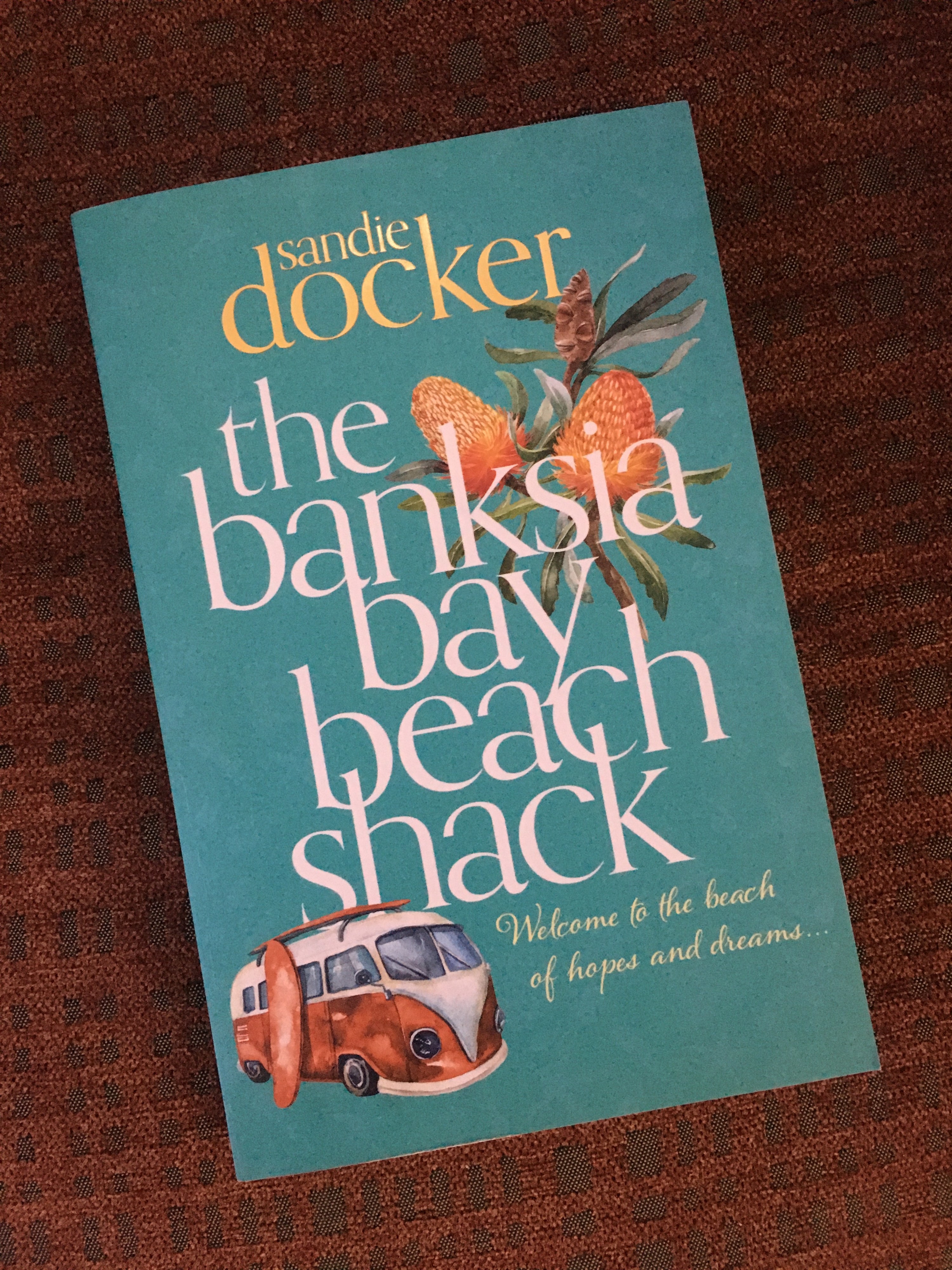 A book with a light cover, a picture of a banksia and old-school van