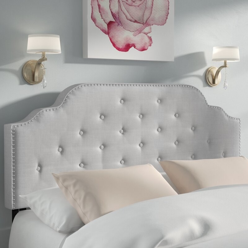 The headboard in gray, which has button-tufting, and a rounded top with multiple arches