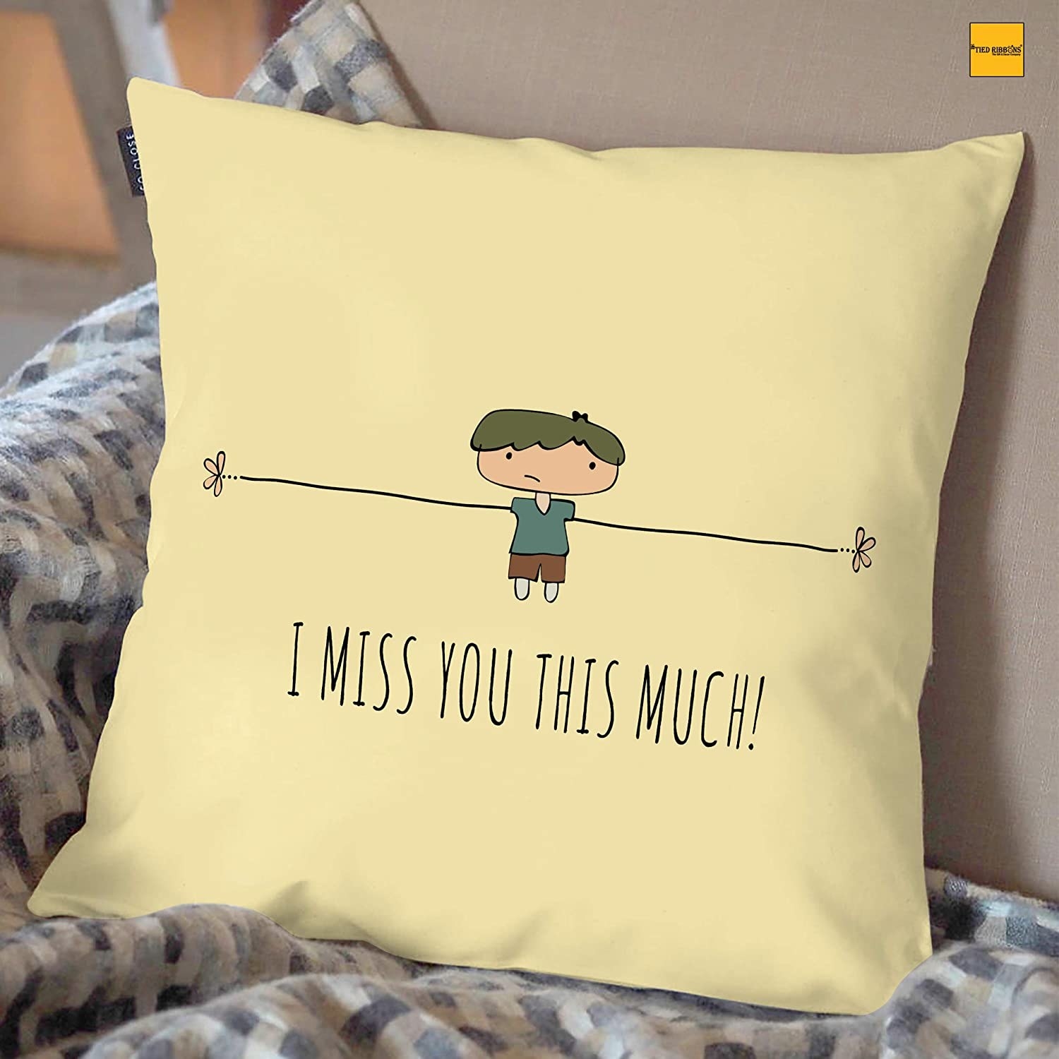 A beige cushion that has a boy with his hands stretched out and the words, &quot;I miss you this much!&quot;.