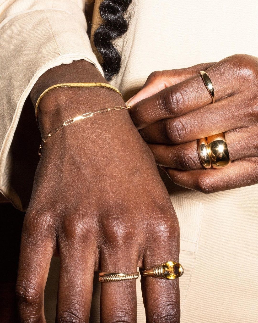 a model's hands with gold rings and bracelets