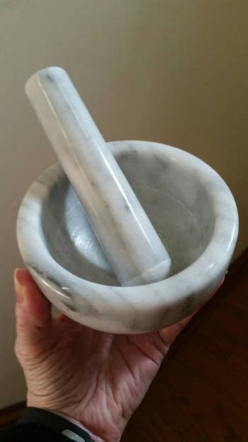 A reviewer holding the mortar and pestle which is the size of an average bowl