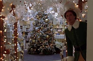 Buddy the Elf standing in front of a well-decorated christmas tree 