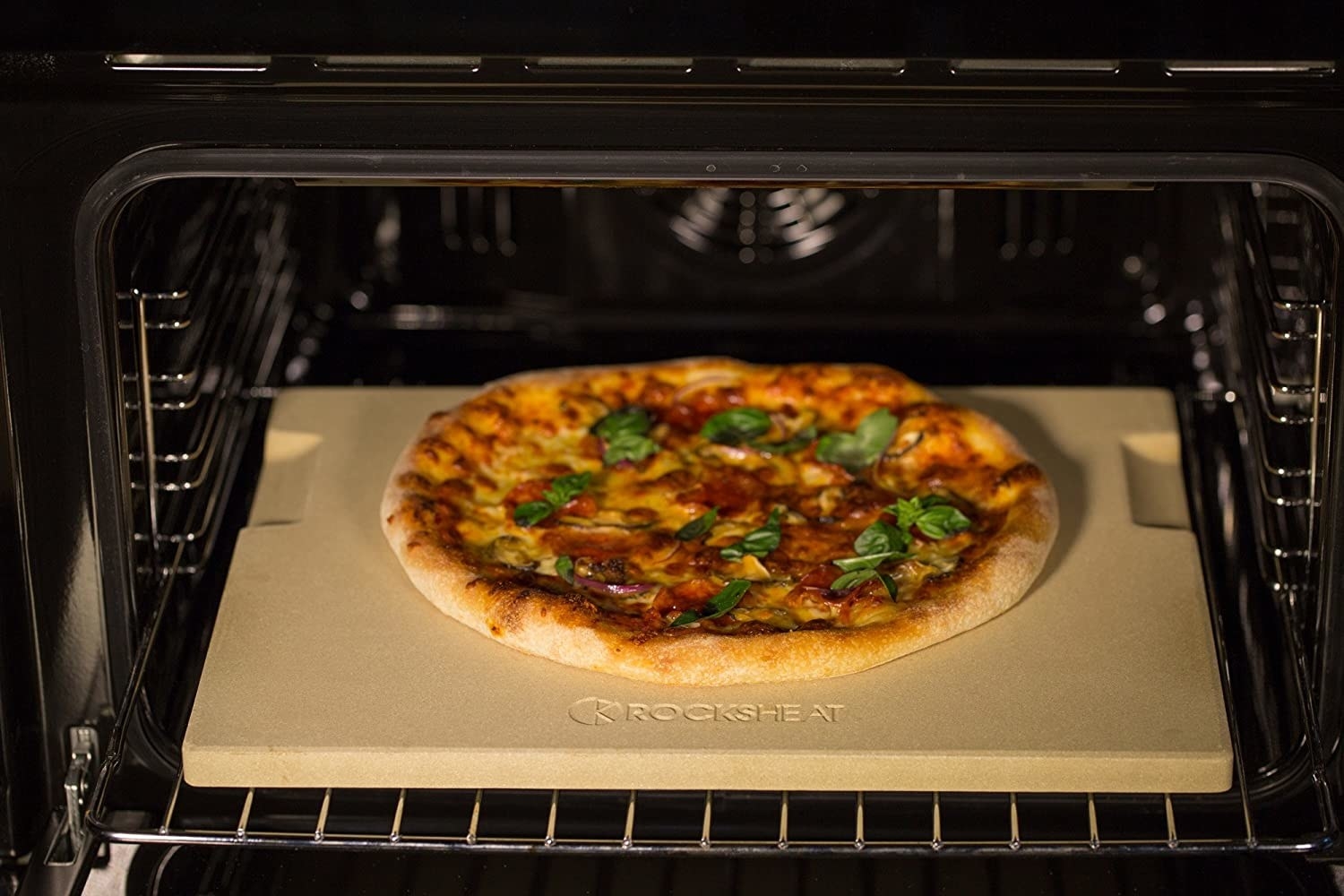 A homemade pizza cooking on the pizza stone in an oven