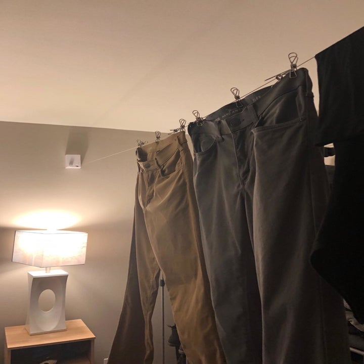 A reviewer photo showing the retractable indoor clothesline mounted on the wall with multiple pairs of pants hanging on it 