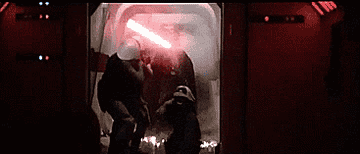 Darth swinging his lightsaber as a man presses a button to close the door on the scene
