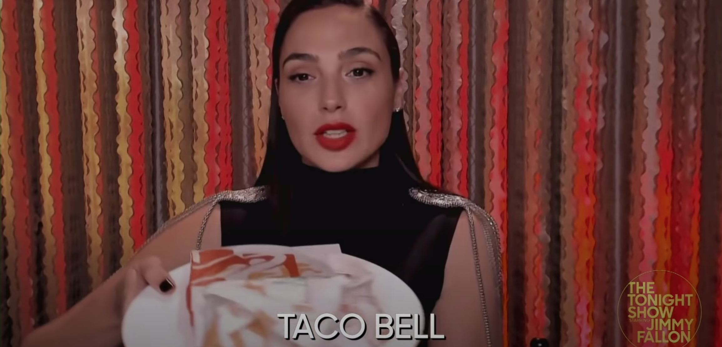 Gal Gadot holds up a plate of wrapped tacos from Taco Bell