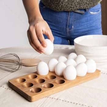 A model grabbing an egg from the wooden holder which can hold 18 eggs 