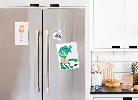 Children's artwork taped to a refrigerator door using Scotch Magic Tape
