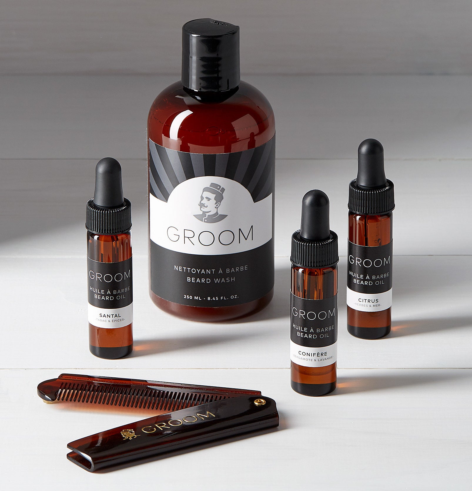 A large bottle of beard wash and three small bottles of beard oil and a small comb