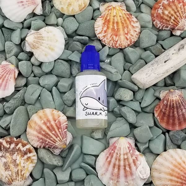 Holy Snails' Shark Sauce container with graphic of smiley shark on a pile of seashells