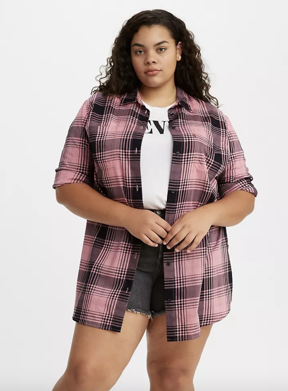 Model in plaid pink and black button up blouse with the long sleeves rolled up 