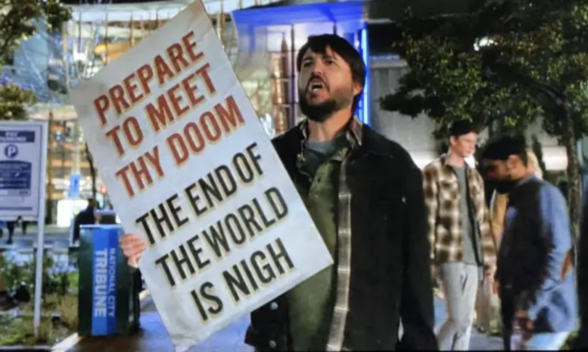 Will Wheaton holds a sign reading: prepare to meet they doom, the end of the world is nigh