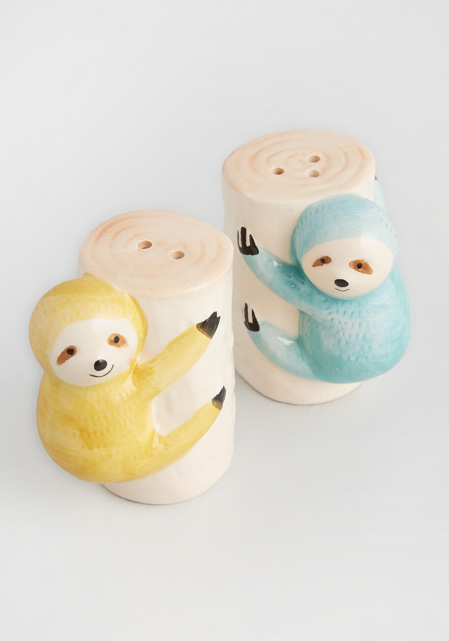 two cylinder shaped salt and pepper shakers with sloths hanging on the sides