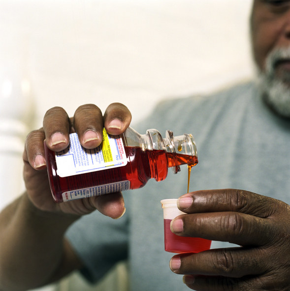 Image of a man pouring cough medicine.