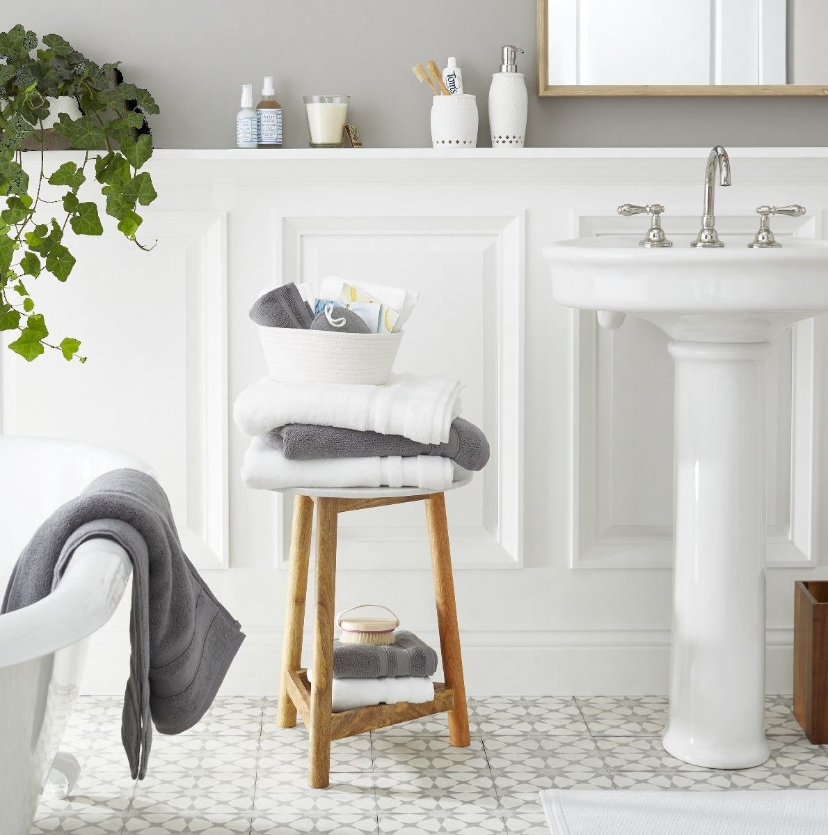 Wood and marble side table with gray and white towels stacked on top