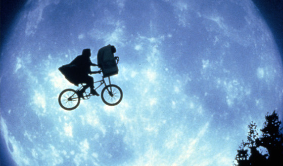 Elliot and ET riding in front of the moon on a flying bike