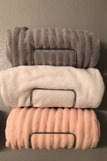 reviewer photo of chrome-color towel rack holding three rolled up towels
