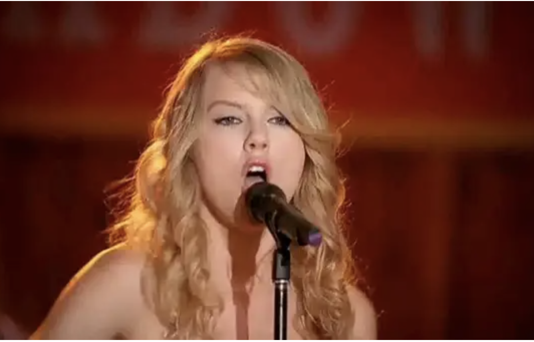 Taylor Swift sings at a microphone