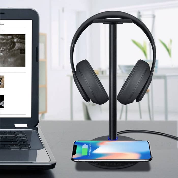 A phone and headset on the stand next to a computer