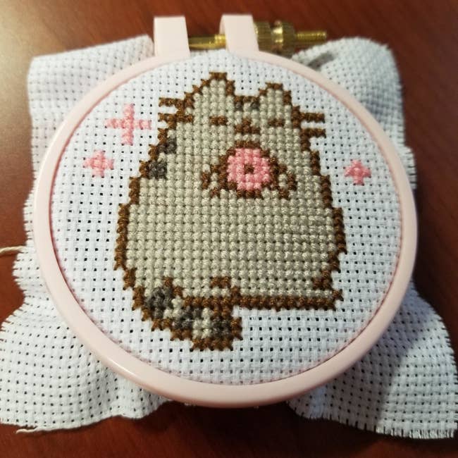 The cross-stitch of Pusheen eating a donut